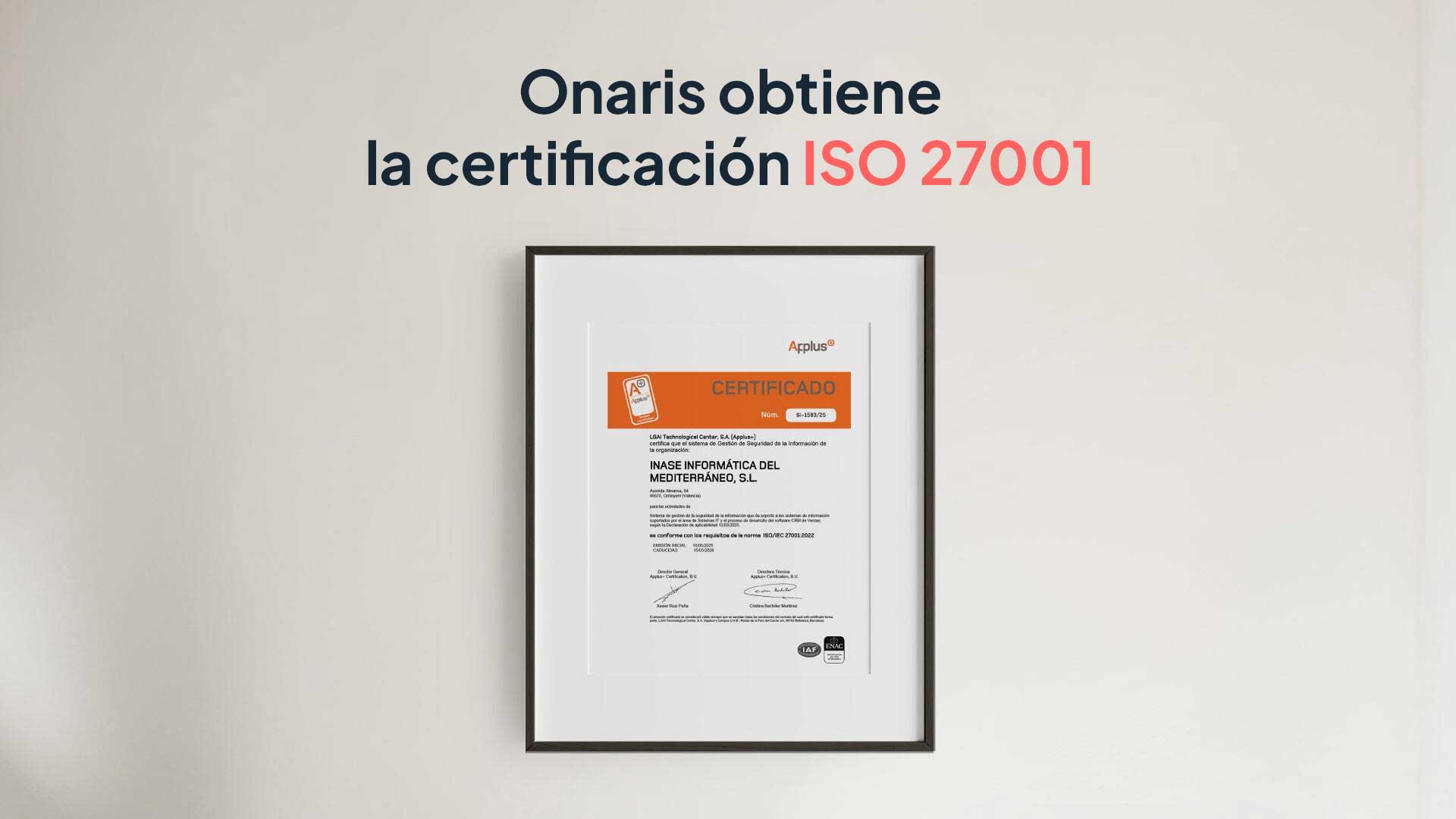 Una certificación ISO 27001 enmarcada cuelga de una pared blanca. Sobre el marco, un texto en español dice: Onaris obtiene la certificación ISO 27001 en letras negras y rojas.