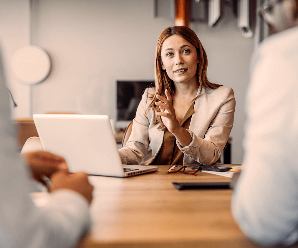 Trabajadora Onaris con su ordenador hablando con dos clientes
